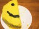 A half cake, with half a smiley face on top