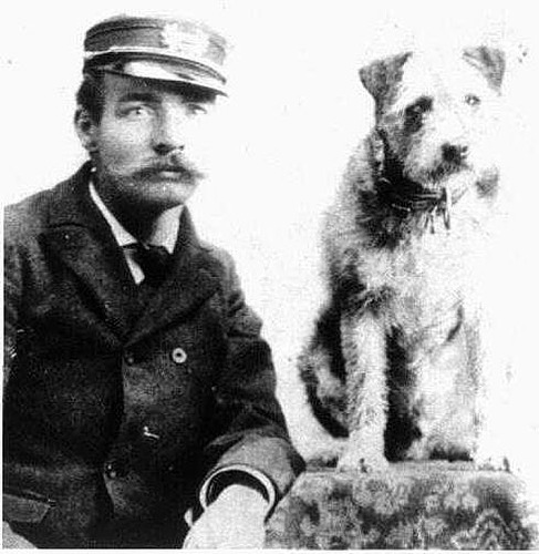 Owney the dog (right) with a railroad worker with a bushy mustache, wearing a uniform. (Photo via the National Postal Museum/Creative Commons https://collections.si.edu/search/record/ark:/65665/hm8af75c3179bea4f46958cacc39c349a82)