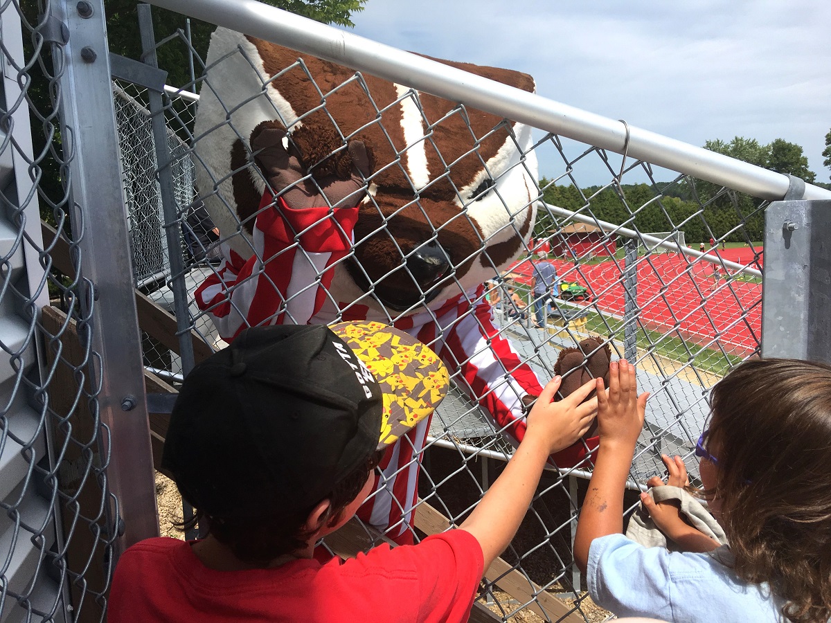 Eight year old and four year old high-five Bucky through the fence