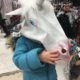 Two year old tries on a unicorn mask