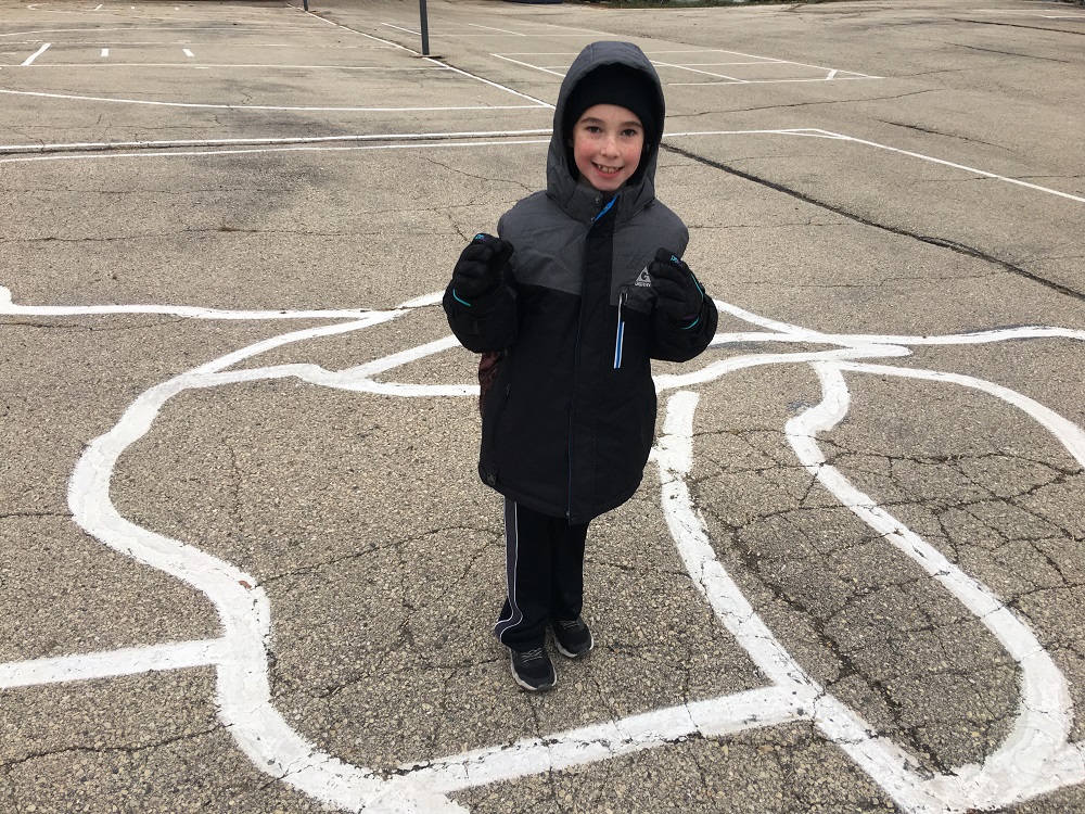 Seven year old stands in a painted map of Wisconsin