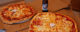 Two round pizzas, cut into square pieces, next to an open bottle of beer. (Photo by Jerry Huddleston via Flickr/Creative Commons https://flic.kr/p/9TLBjx)