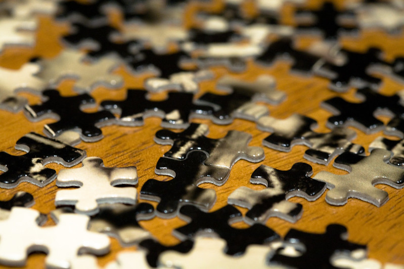 Pieces of a jigsaw puzzle on a table, not yet put together. (Photo by Liza via Flickr/Creative Commons https://flic.kr/p/5ubRQX)