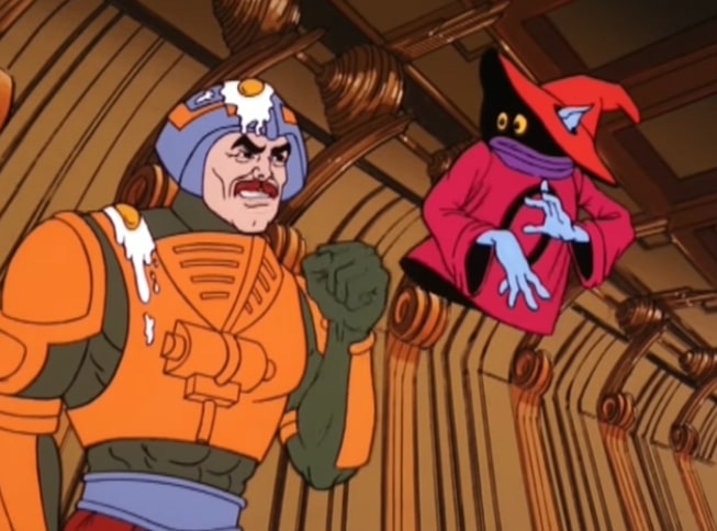 Man-at-Arms is covered in eggs and shaking his fist at Orko