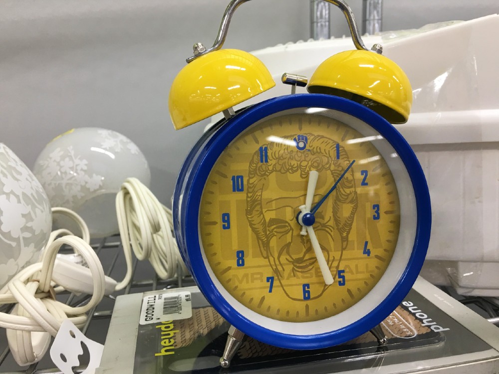 A blue and yellow old-school alarm clock, with bells on top and a drawing of Bob Uecker's head on the face.