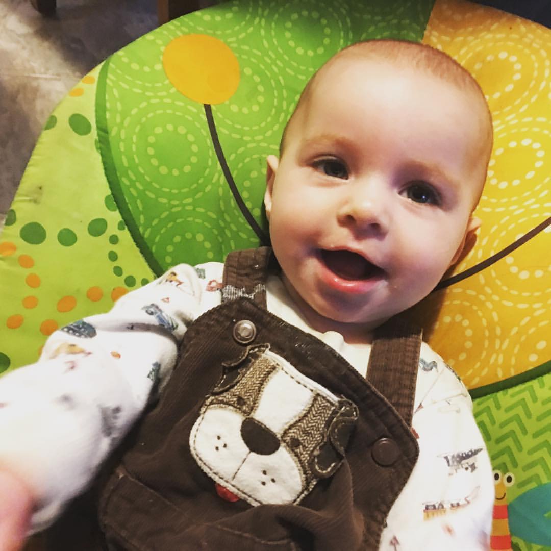Six month old is smiling while wearing her brown overalls with a dog in the front. Awww.