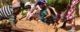 Women in colorful clothes plant seeds in light brown dirt. (Photo via GreatGreenWall.org)