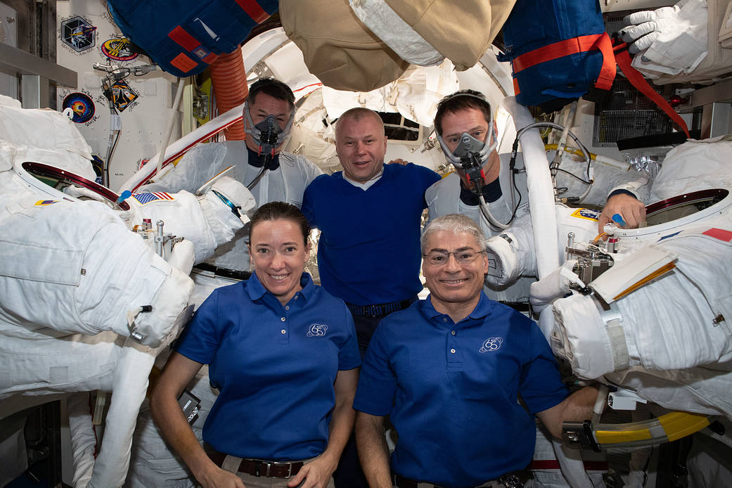 At center in the blue shirts, are (clockwise from bottom left) Expedition 65 Flight Engineers Megan McArthur, Oleg Novitskiy and Mark Vande Hei. The trio is posing with astronauts (from left) Shane Kimbrough and Thomas Pesquet who were preparing for a spacewalk to install new roll out solar arrays on the International Space Station's P-6 truss structure. (Photo via NASA https://www.nasa.gov/image-feature/expedition-65-crew-members-supporting-spacewalkers)