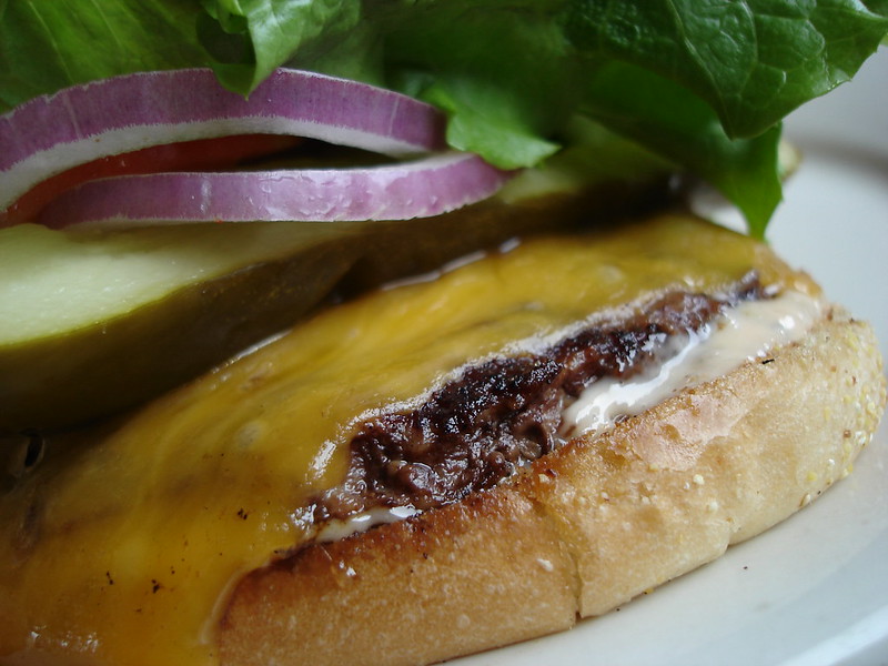 A cheeseburger with lettuce, red onion and pickle. (Photo by Elliot Leuthold via Flickr/Creative Commons https://flic.kr/p/BUisd)