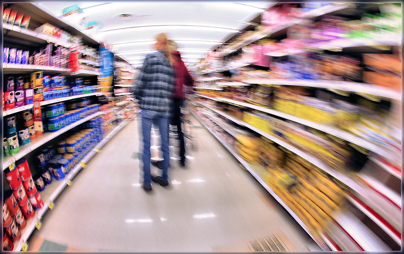 An artistically blurry photo of two people grocery shopping. (Photo by Indiana Stan via Flickr/Creative Commons https://flic.kr/p/ayKEh5)