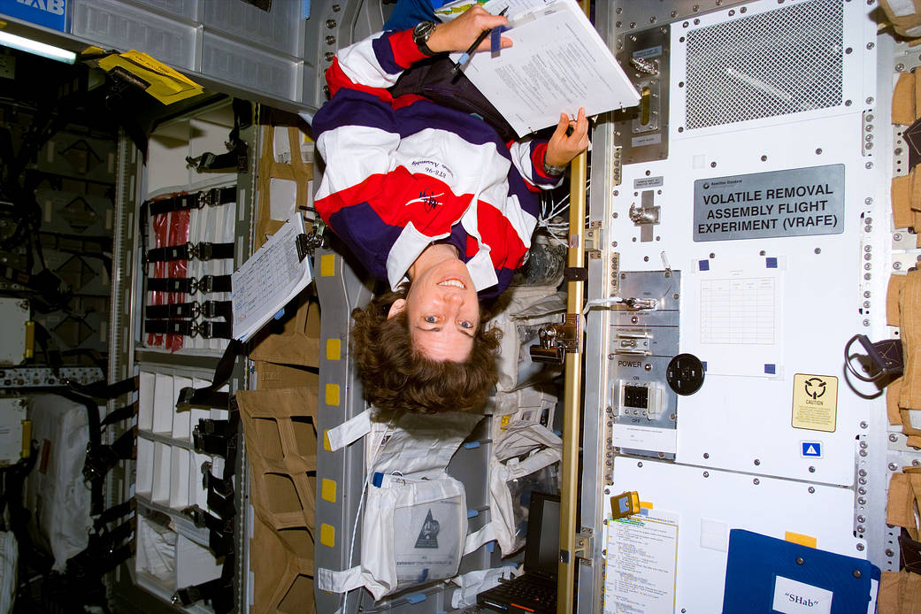 Dr. Ellen Ochoa reads a checklist while floating upside down on Space Shuttle Discovery in 1999. (Photo via NASA https://www.nasa.gov/image-feature/ellen-ochoa-at-work-on-the-shuttle)