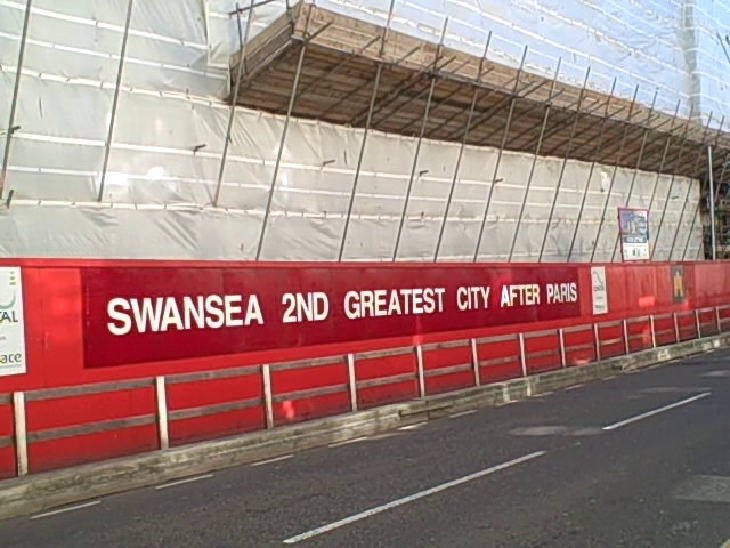 A red sign with white letters proclaims "Swansea 2nd greatest city after Paris." This is not the sign the episode is about, to be clear. (Photo by Carl Morris via Flickr/Creative Commons https://flic.kr/p/9QWSDx)