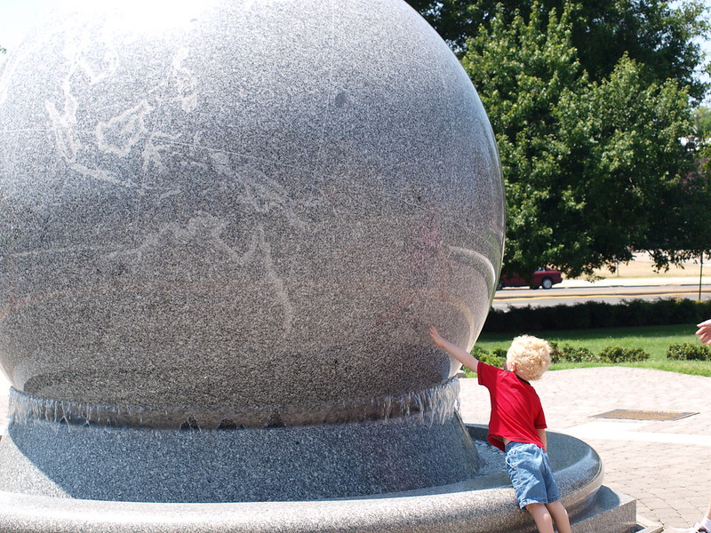 A youngster pushes the Grand Kugel, a giant grey stone ball. (Photo by rmanoske via Flickr/Creative Commons https://flic.kr/p/a8v85X)