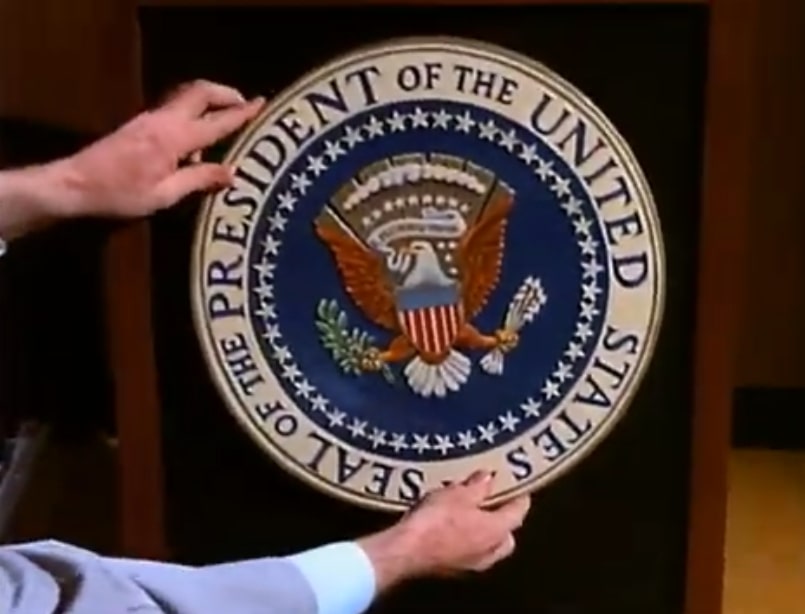 Agent Franke puts the presidential seal on a podium.