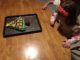 Four year old looks at her sheet cake, which is shaped like and decorated like a Christmas tree.