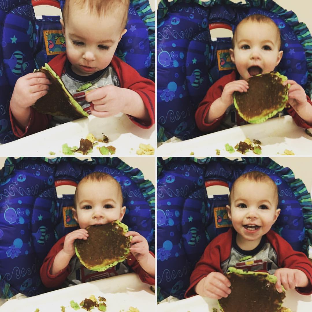 One year old is enjoying eating a large green pancake!