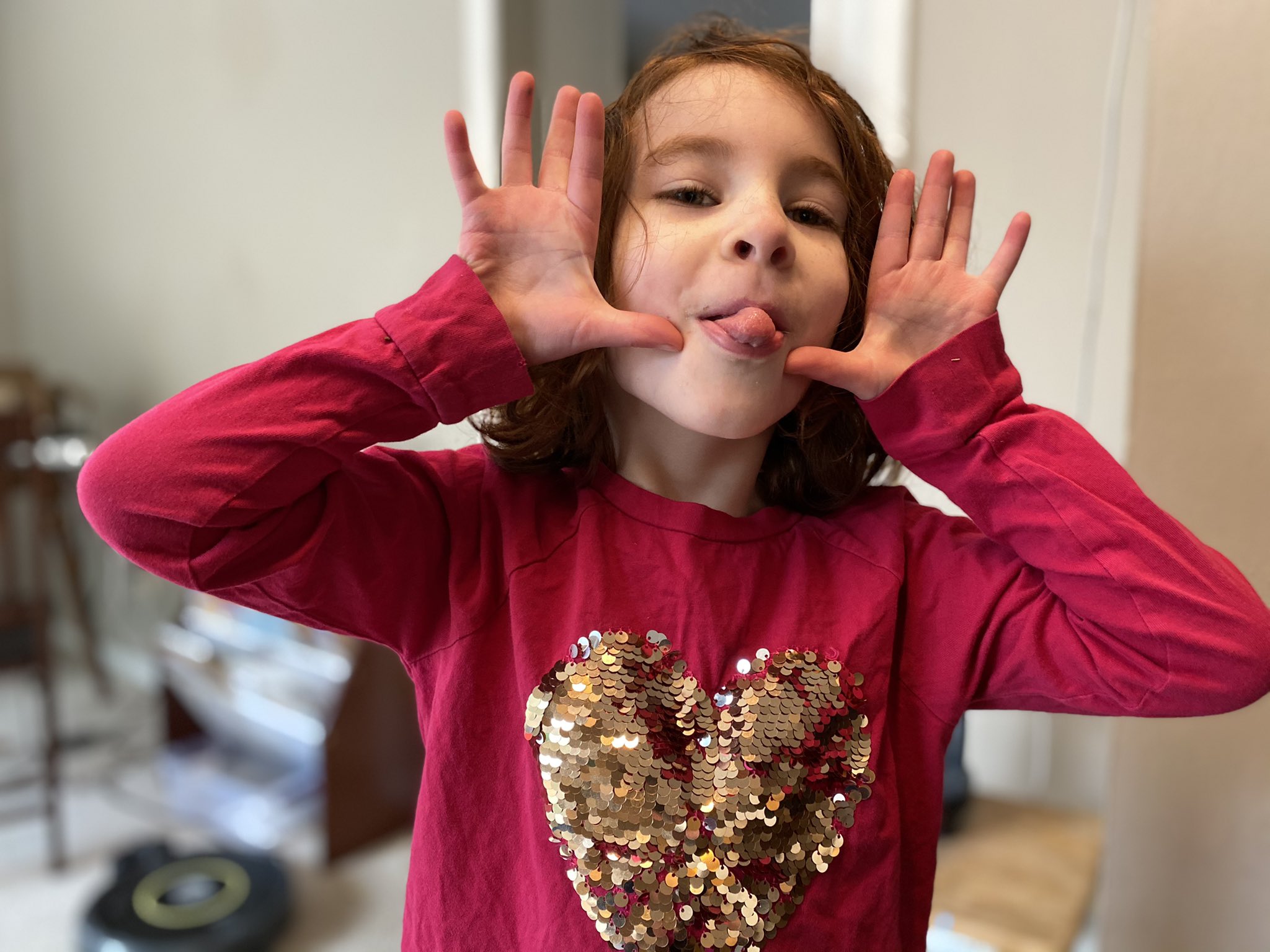 Five year old puts up both her hands and sticks out her tongue.