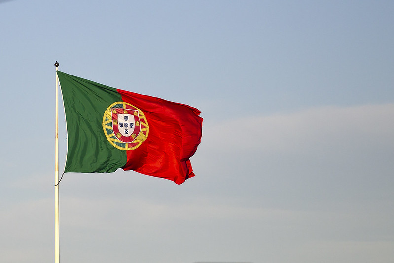 The national flag of Portugal: a bar of green on the left, red on the right, and the country's coat of arms near the center. (Photo by Ted van den Bergh via Flickr/Creative Commons https://flic.kr/p/ejbckk)