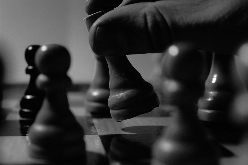 A hand moves a chess piece. (Photo by Eigenberg Fotografie via Flickr/Creative Commons https://flic.kr/p/hWQv4r)
