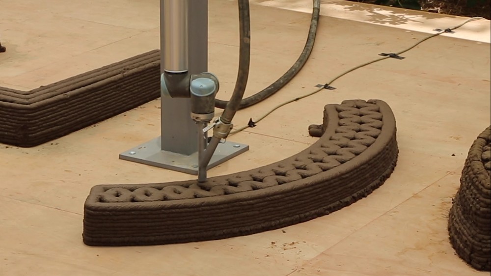 Screenshot of the demo video for To Grow A Building, in which a 3D printer prints rows in the soil wall.