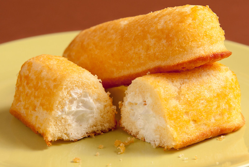 Two Twinkies on a yellow plate, one of them cut in half to show the cream filling. (Photo by Christian Cable via Flickr/Creative Commons https://flic.kr/p/7Ywntm)