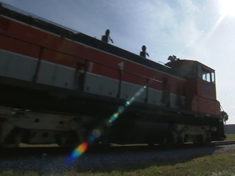 A red locomotive with the NASA logo on its side in action. (Screenshot from NASA's Kennedy Space Center via YouTube, https://youtu.be/VybS9Smkuss)