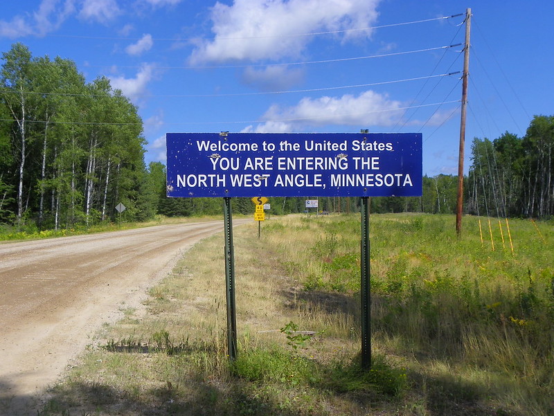 A blue sign reads, "Welcome to the United States - You are entering the North West Angle, Minnesota." (Photo by J. Stephen Conn via Flickr/Creative Commons https://flic.kr/p/agbys4)