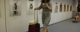 A woman checks her smartphone while rolling her wheeled suitcase through an airport. (Photo by Matthew Hurst via Flickr/Creative Commons https://flic.kr/p/dmpbvA)