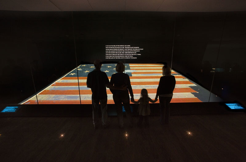 Four people view the original Star-Spangled Banner at the Smithsonian's National Museum of American History. (Photo by National Museum of American History via Flickr/Creative Commons https://flic.kr/p/818rtT)