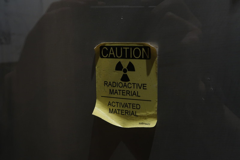 A yellow and black sign reads: "CAUTION: RADIOACTIVE MATERIAL - ACTIVATED MATERIAL." (Photo by Kelly Michals via Flickr/Creative Commons https://flic.kr/p/2nLAHFg)