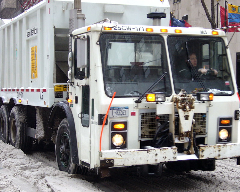A large white garbage truck in New York (not the one in the episode). (Photo by Phil Hollenback via Flickr/Creative Commons https://flic.kr/p/BDDh9)
