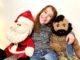 Seven year old smiles as she sits with our plush Santa Claus and Mr. T.