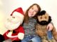 Seven year old smiles as she sits with our plush Santa Claus and Mr. T. 