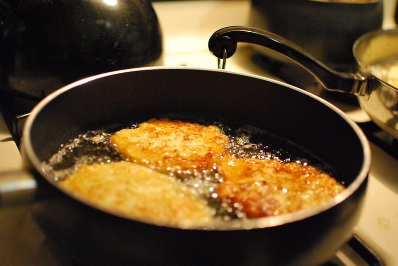 Three latkes frying in a pan. (Photo by slgckgc via Flickr/Creative Commons https://flic.kr/p/7niMbe)