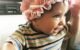 One and a half year old wears an old-looking pink hat and smiles